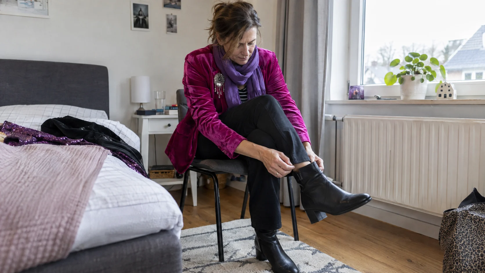 Vrouw in een roze carnavalsjasje die de pasvorm van haar zwarte laars controleert